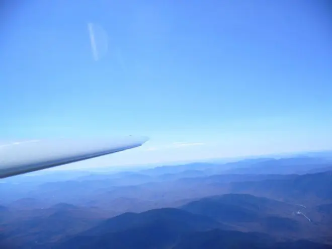 A wingtip over blue ridges stretching into the distance